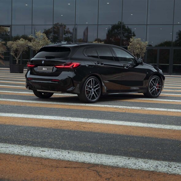 BMW-1-Serie-zwart-achterkant-bloembakken-gele-strepen-witte-strepen-weg-mobiel