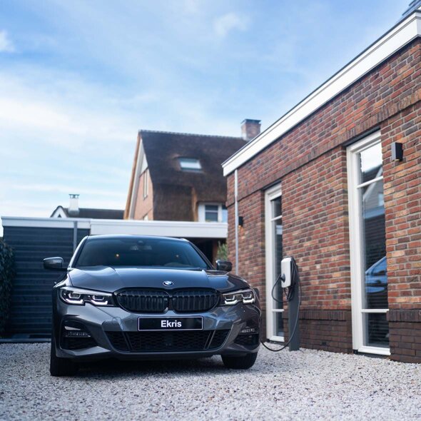 BMW-3-Serie-Sedan-hybride-grijs-voorkant-grindpad-laden-laadpaal-thuis-mobiel