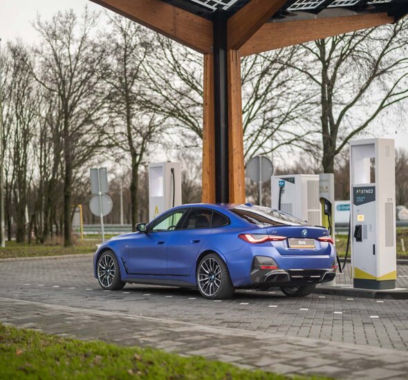 BMW-i4-matblauw-zijkant-achterkant-opladen-fastned-onderweg-mobiel