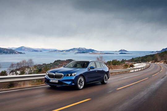 BMW-5-Touring-Blauw-Voorkant-Rijdend-Water-Bergen